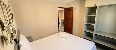 Un dormitorio con cama, armario y aire acondicionado instalado en la pared.