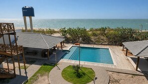 Zona de piscina con vista al océano, un depósito de agua y mobiliario exterior.