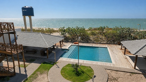 A pool area with a view of the ocean, a water tank, and outdoor seating.