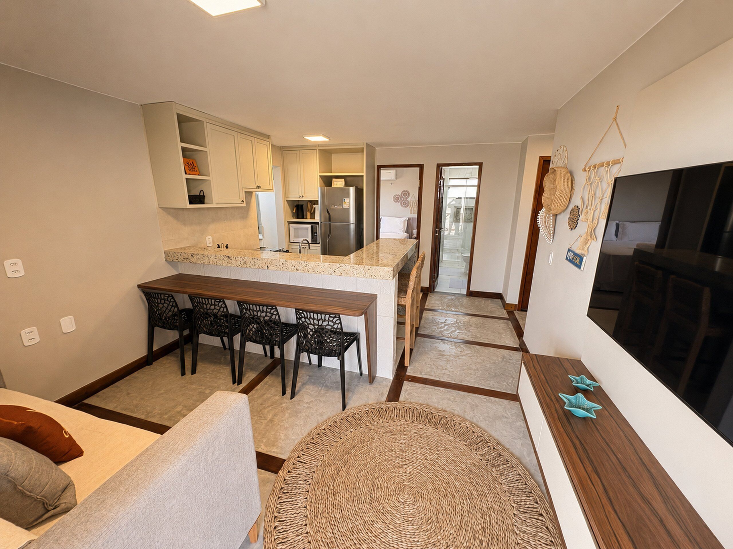 A compact living space with a kitchenette, dining area, and a large TV.