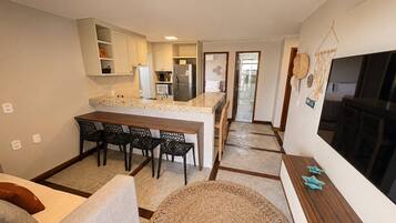 A compact living space with a kitchenette, dining area, and a large TV.