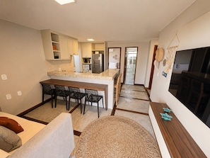 A compact living space with a kitchenette, dining area, and a large TV.