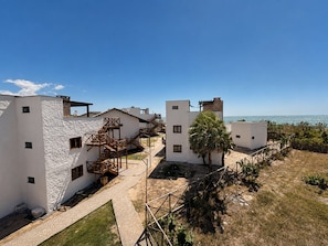 Complejo de edificios costeros con varias estructuras blancas, escaleras de madera y una palmera.