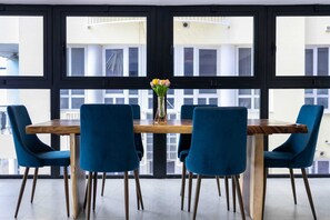 A dining area with a wooden table, four blue chairs, and a vase with flowers. - Handelskade's Grand Historical Penthouse: Refined Luxury Living (Willemstad)