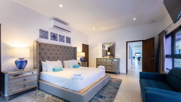 Een moderne hotelkamer met een groot bed, nachtkastjes, een kaptafel en een spiegel.