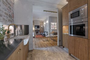 Eine moderne Küche mit Edelstahlgeräten, Holzschränken und einer sichtbaren Backsteinwand.