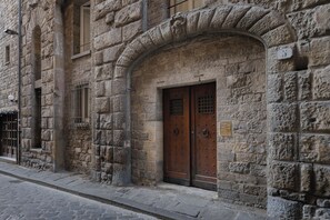 A stone building with a wooden door and a small plaque. - 2BR • Luxury Tower-House • Prime Location •  Ponte Vecchio • Quaint• Elegance (Firenze)