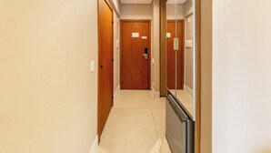Um corredor com portas de madeira e um espelho à direita.