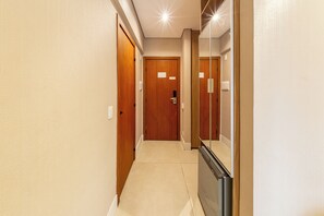 A hallway with wooden doors and a mirror on the right. - Address by Bhomy (São Paulo)