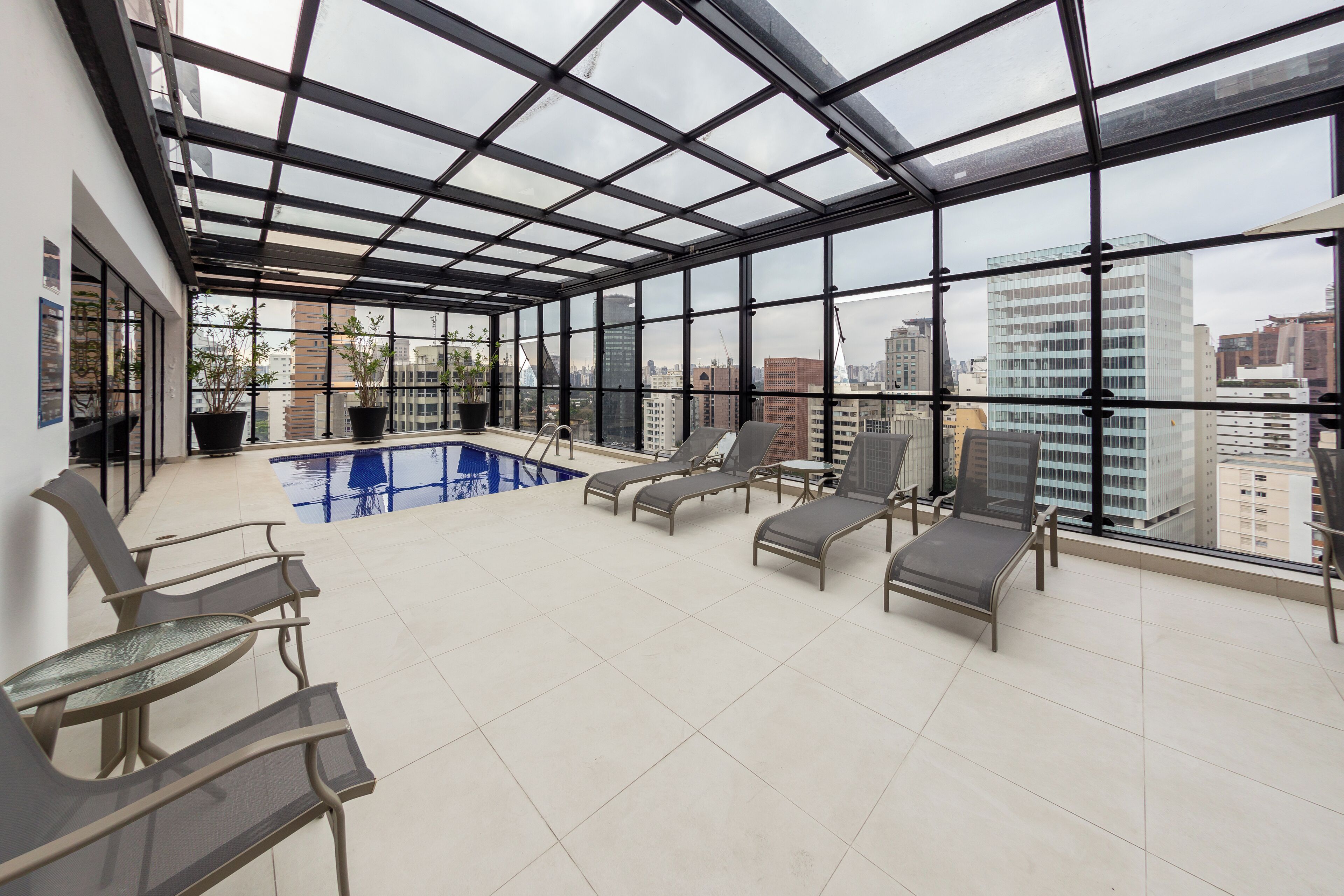 A rooftop terrace with a swimming pool, lounge chairs, and a city view.