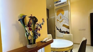 A dining area with a round table, chairs, a vase with flowers, and a wall-mounted air conditioner. - AA SERVICE APARTMENT (Akure)