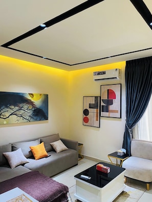 A modern living room with a sofa, a coffee table, a TV, and artwork on the walls. - AA SERVICE APARTMENT (Akure)