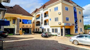A multi-story hotel with a central courtyard, balconies, and a parking area. - AA SERVICE APARTMENT (Akure)