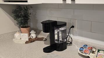 A kitchen with a microwave, coffee maker, and a marble countertop.
