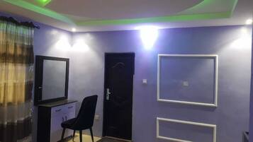 Una habitación con una puerta negra, un espejo, una silla y una pared con dos marcos rectangulares.