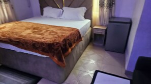Un dormitorio con cama, mesita de noche y un mueble pequeño.