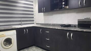 Una cocina con armarios oscuros, lavadora y microondas.