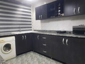 Una cocina con armarios oscuros, lavadora y microondas.