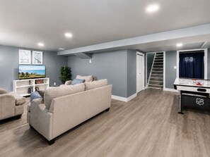 A modern living room with a sofa, a flat-screen TV, and a bookshelf.