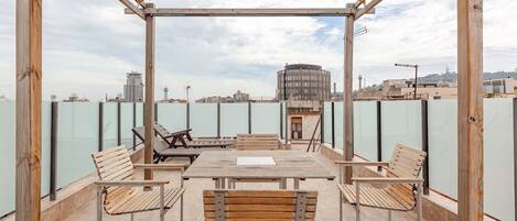 Eine Außenterrasse mit Holzmöbeln, einer Pergola und Blick auf die Stadtlandschaft.