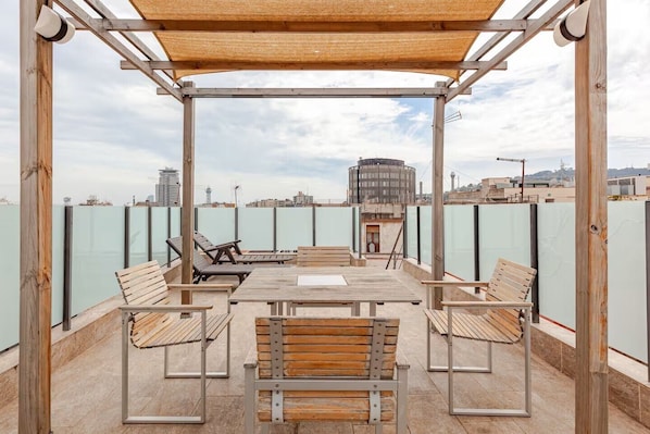 An outdoor terrace with wooden furniture, a pergola, and a view of the cityscape. - Intimate rooftop terrace with a hot tub and 360° views of Barcelona (Barcelona)