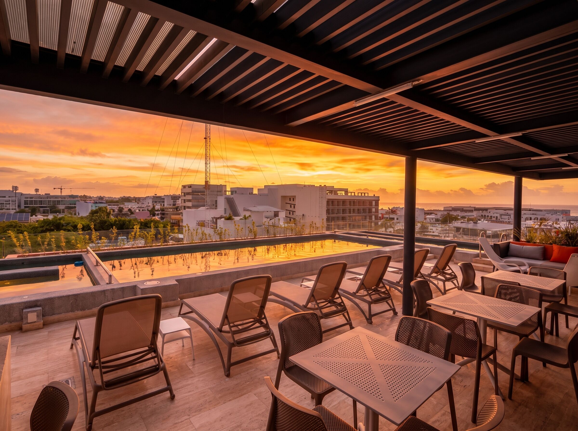 Terraza en la azotea con mobiliario exterior y vistas a la ciudad al atardecer.