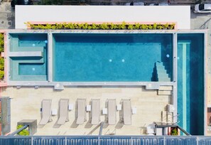 An outdoor swimming pool with a separate children's pool, multiple lounge chairs, and a small table area. - Luxury loft in the heart of Playa del Carmen Stunning Rooftop Pool and Jacuzzi (Playa del Carmen)