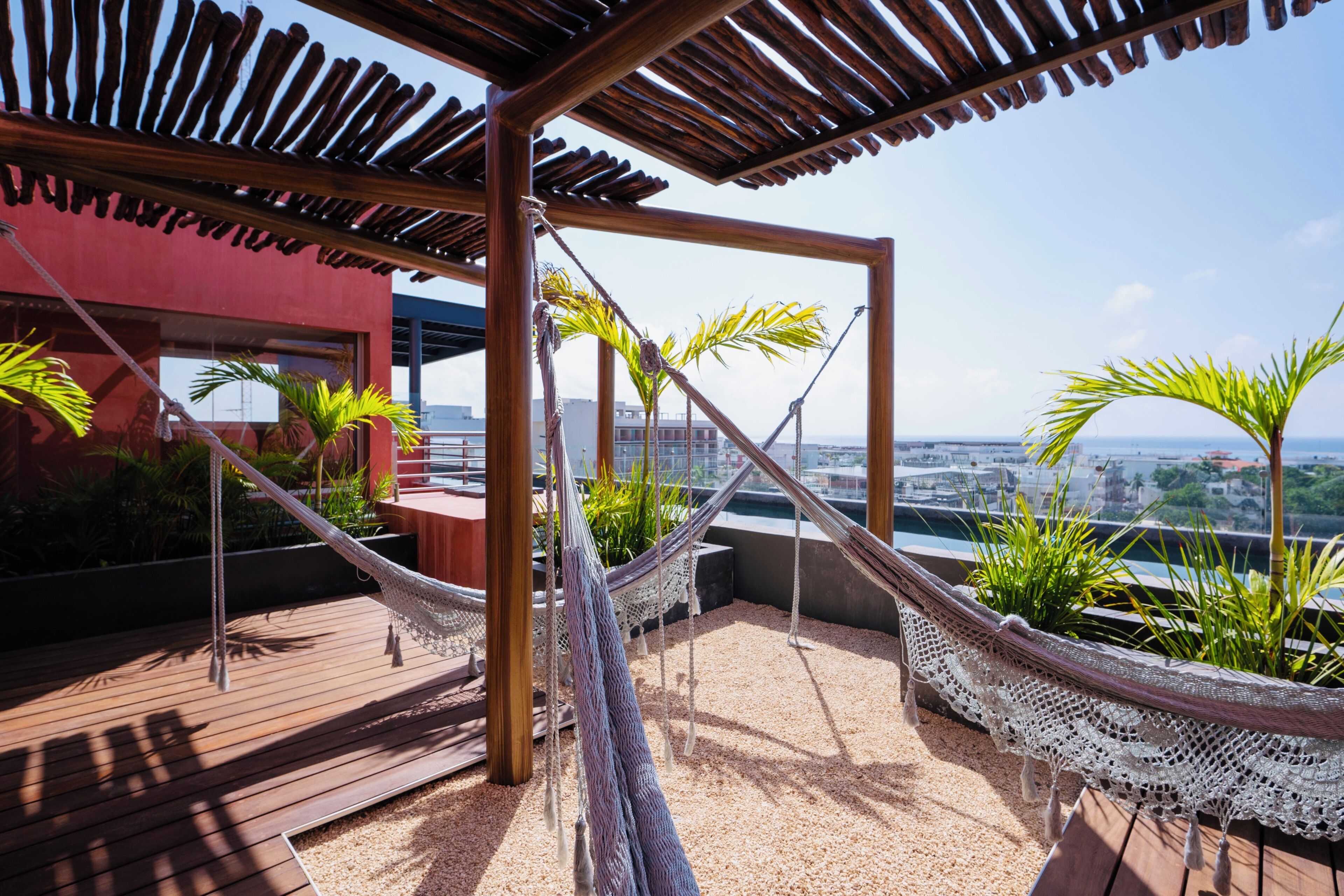 A rooftop terrace with a wooden pergola, a hammock, and potted plants.