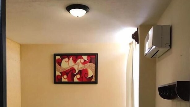 A hotel room with a bed, a nightstand, a bedside table, a wall-mounted air conditioner, and a framed abstract painting. - Hotel Frailes (Arriaga)