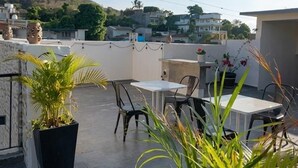 An outdoor patio with tables and chairs, potted plants, and a view of the surrounding neighborhood. - Hotel Frailes (Arriaga)