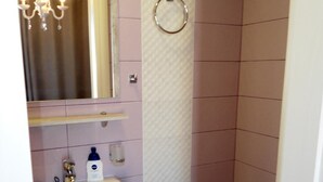 Un baño pequeño con lavamanos, espejo, inodoro y toallero.
