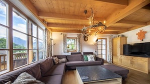 Ein gemütliches Wohnzimmer mit einem Ecksofa, einem Couchtisch und einem Fernseher.