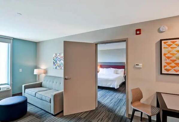 Ein Hotelzimmer mit einer Schlafcouch, einem Sessel, einem Bett und einem Schreibtisch.