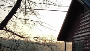 Una baita con una terrazza che si affaccia su un lago, circondata da alberi.