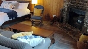 Una stanza accogliente con un letto, un divano, una poltrona, un camino e un soffitto in legno.