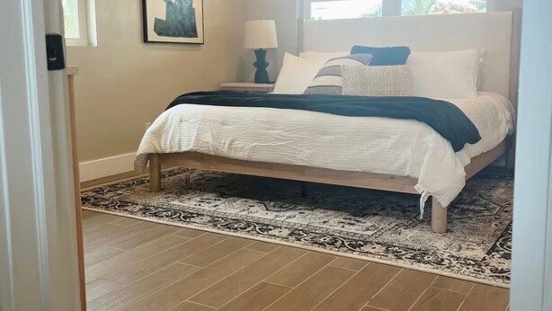 Un dormitorio con cama, ventilador de techo, ventana y alfombra.