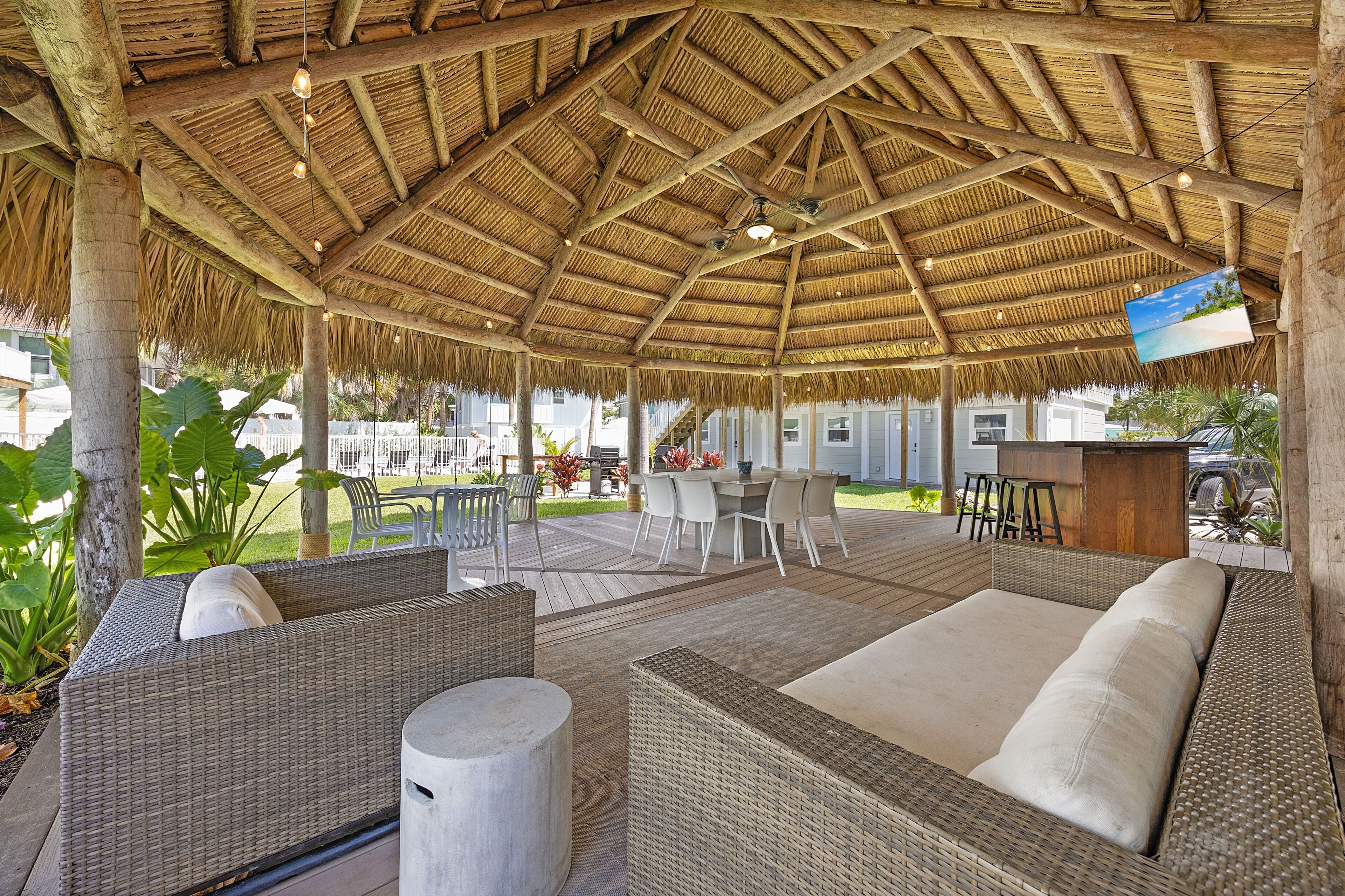 An outdoor seating area with wicker furniture and a thatched roof.