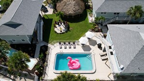 Una propiedad residencial con piscina, una construcción con techo de paja y un patio cercado.