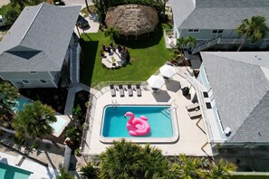 Ein Wohnhaus mit Schwimmbad, einem Reetdachgebäude und einem umzäunten Patio.