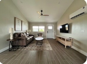 Ein Wohnzimmer mit Sofa, Couchtisch, Fernseher und Deckenventilator.