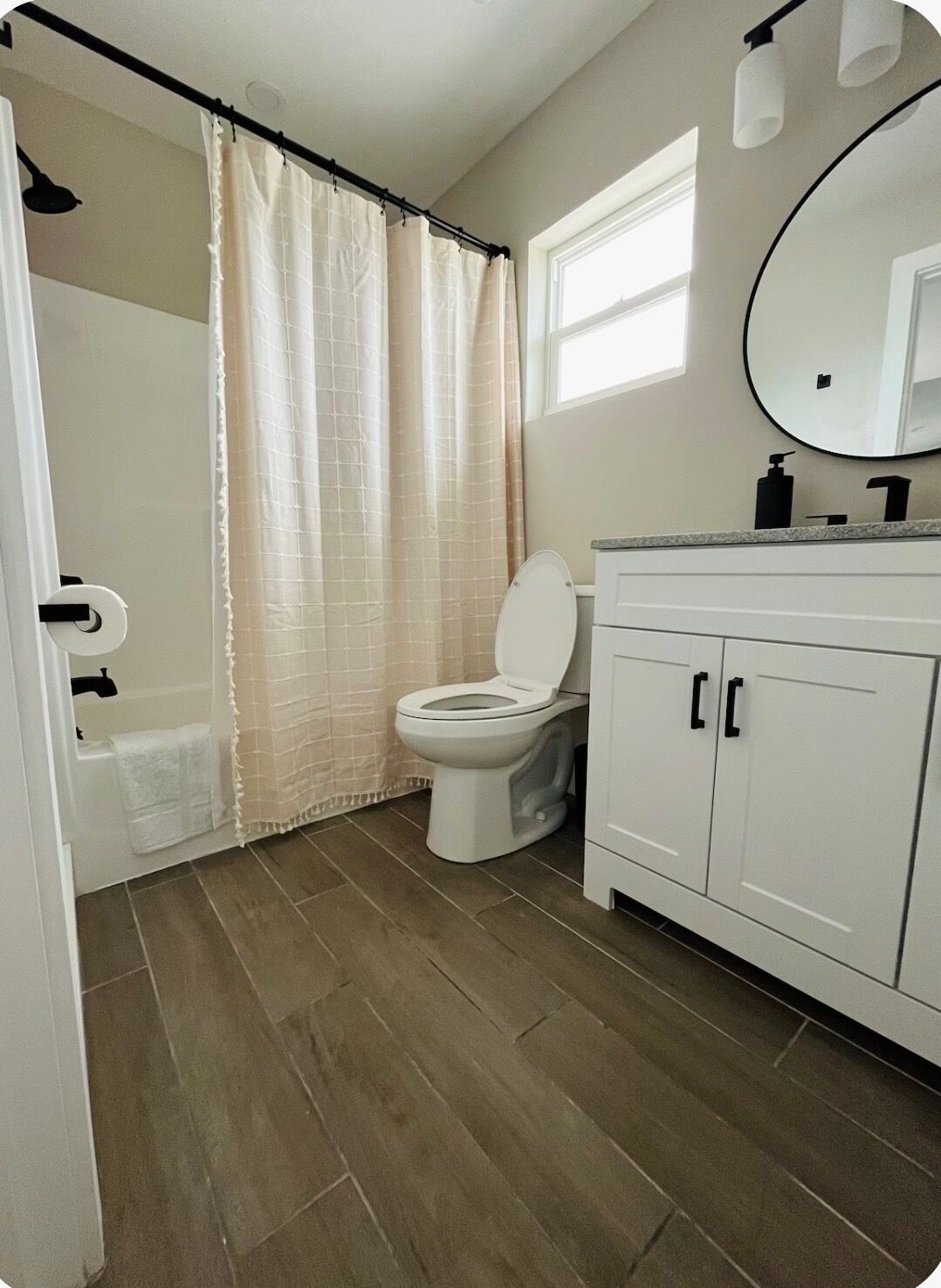 Une salle de bain comprenant des toilettes, un rideau de douche, un lavabo avec un miroir et un porte-serviettes.