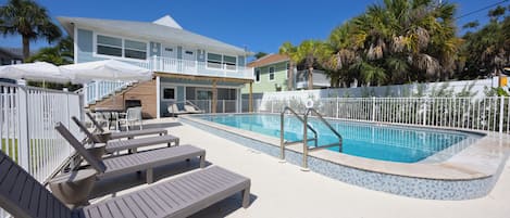 A pool area with lounge chairs and a building in the background.