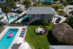 A two-story building with a swimming pool, a thatched roof structure, and a well-maintained lawn. - The Wells (Fort Myers Beach)