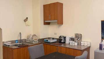 A compact kitchen with a dining area, equipped with a sink, stove, and various appliances.