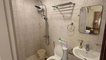 A bathroom with a toilet, sink, shower, and a towel rack.