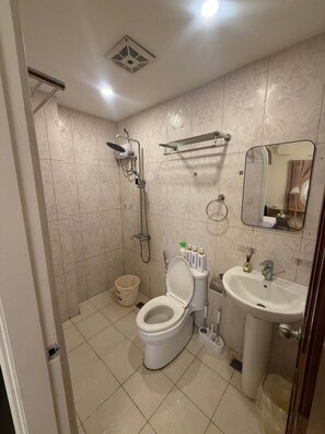 A bathroom with a toilet, sink, shower, and a towel rack. - Boracay Affordable Stay (Malay)