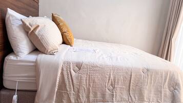 A neatly made bed with a white duvet, two pillows, and a tag on the bed.