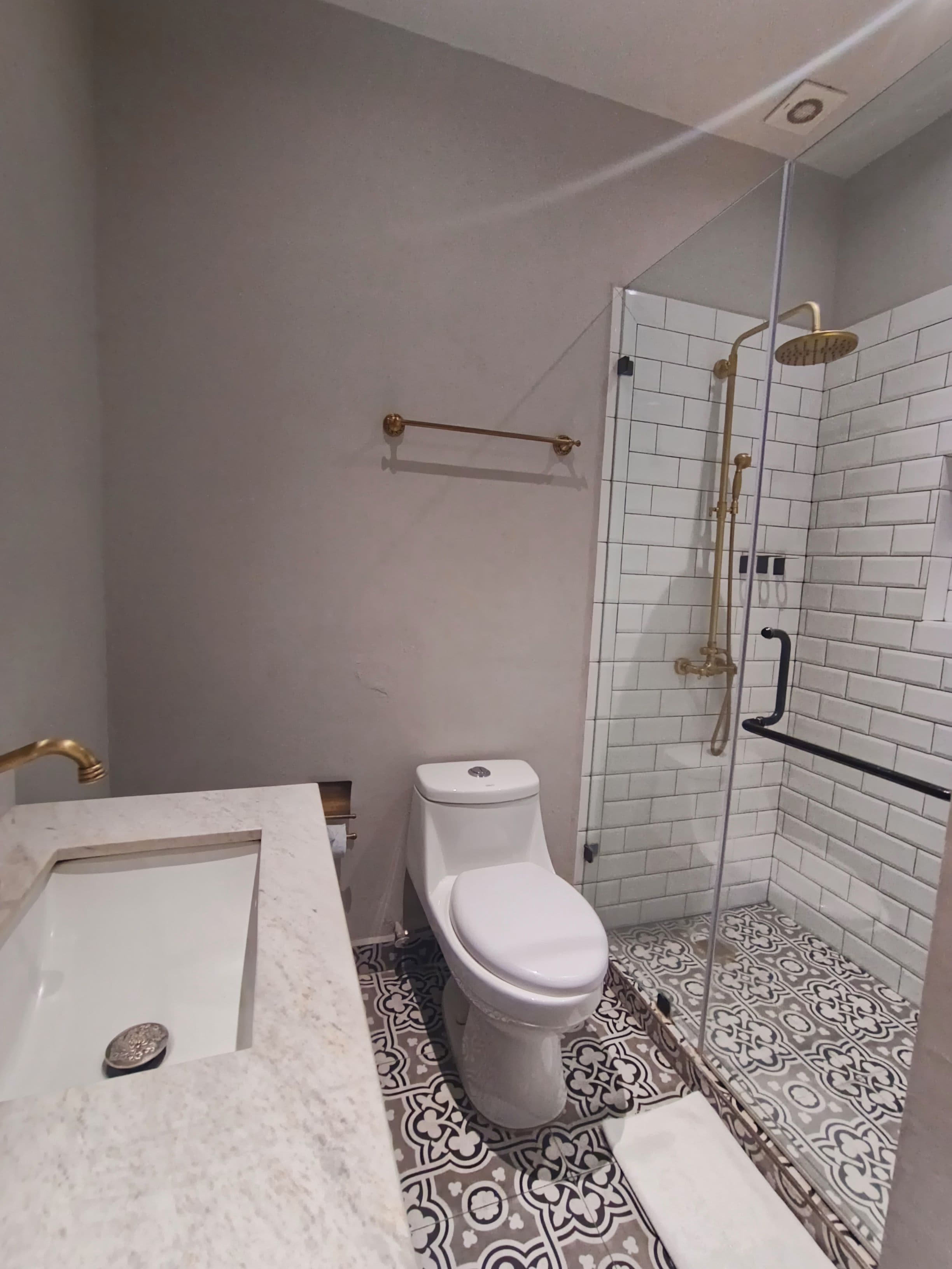 Un baño con inodoro blanco, ducha con puerta de cristal y lavamanos de mármol.