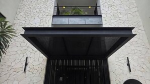 Ein Gebäude mit einer Stein-Fassade, einem schwarzen Eingang und einem Schild, das auf ein Geschäft hinweist.