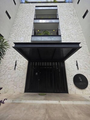 A building with a stone facade, a black entrance, and a sign indicating a business. - Condo 2 recámaras a pasos de playa Santa Cruz (Bahía de Santa Cruz Huatulco)